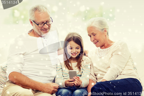Image of smiling family with smartphone at home