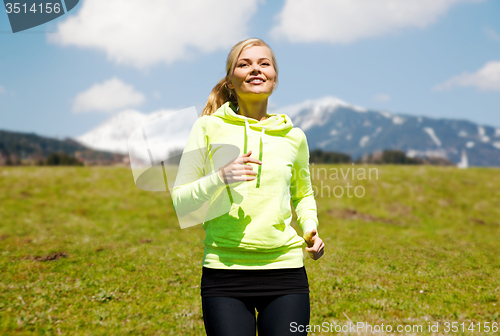 Image of happy young smiling woman jogging outdoors