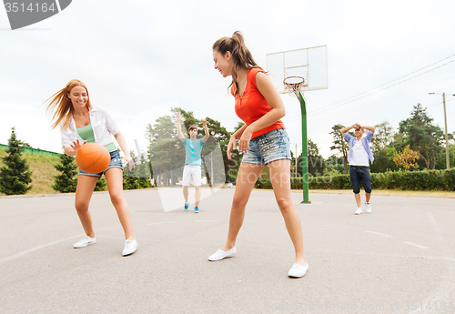 Image of group of happy teenagers playing basketball