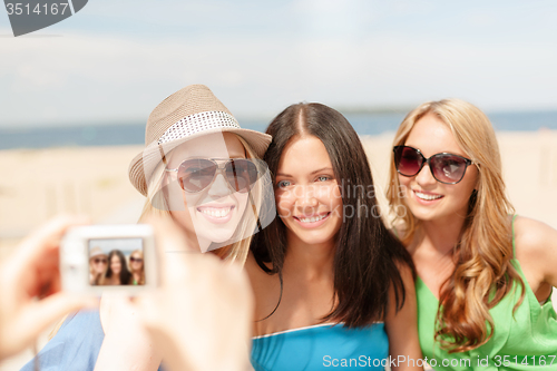 Image of girls taking photo with digital camera in cafe