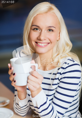 Image of happy young woman drinking tea or coffee