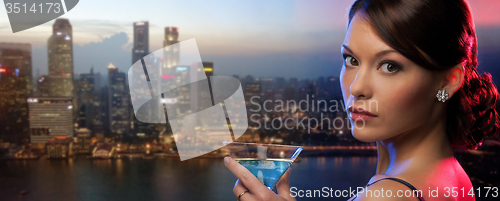 Image of woman holding cocktail over singapore night city