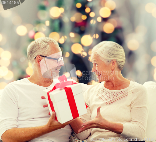 Image of happy senior couple with gift box at home