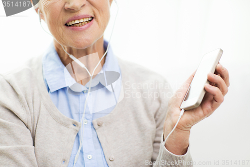 Image of happy senior woman with smartphone and earphones