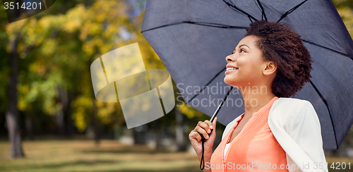 Image of happy african woman with umbrella in autumn park 