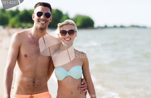 Image of happy couple in swimwear walking on summer beach