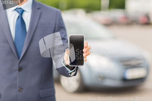 Image of close up of business man with smartphone and car