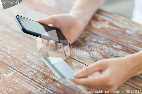 Image of close up of hands with smart phone and credit card