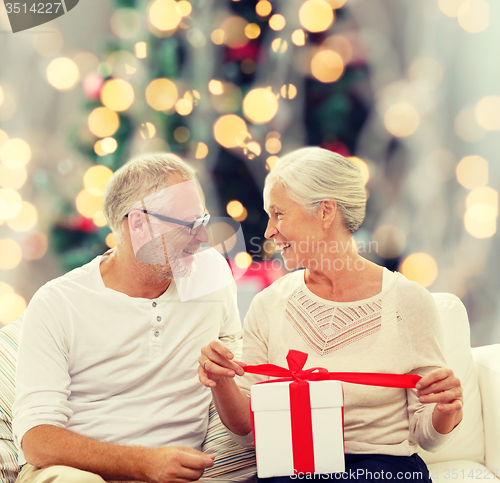 Image of happy senior couple with gift box at home