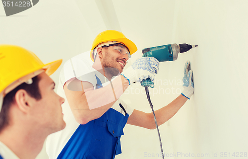 Image of group of smiling builders with drill indoors