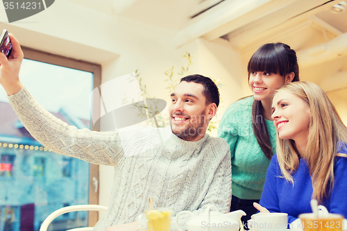 Image of group of friends taking selfie with smartphone