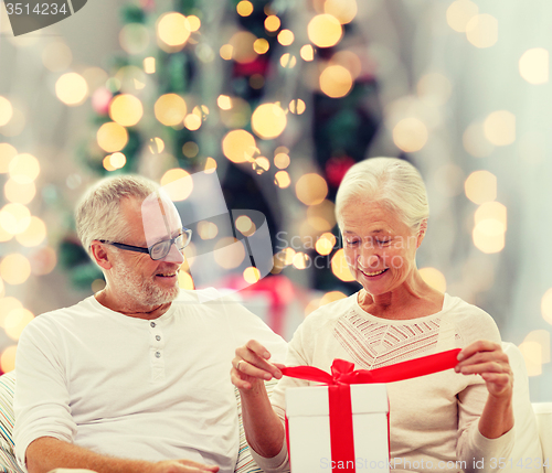 Image of happy senior couple with gift box at home