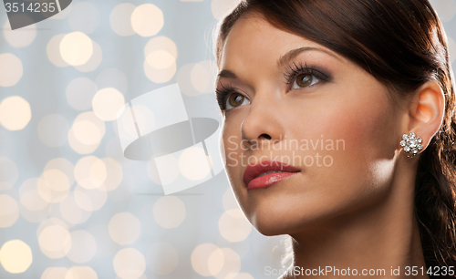 Image of woman with diamond earring over holidays lights