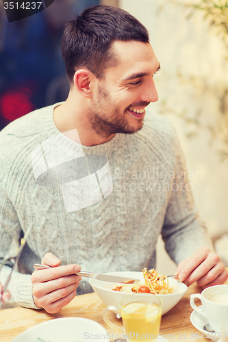 Image of happy young man having dinner at restaurant