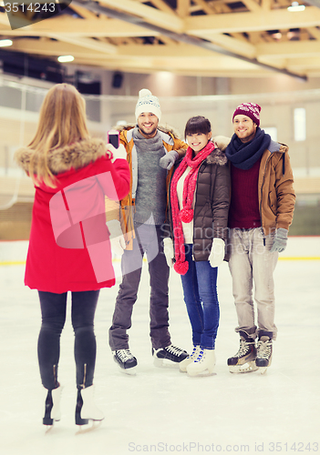 Image of happy friends taking photo on skating rink