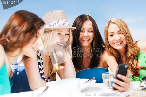Image of girls looking at smartphone in cafe on the beach