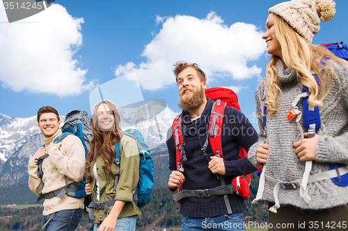 Image of happy friends with backpacks hiking over mountains