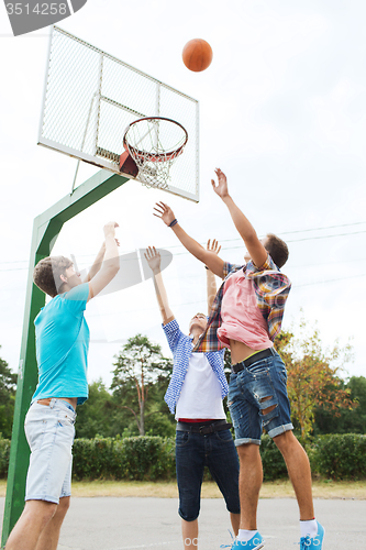 Image of group of happy teenage friends playing basketball