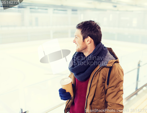 Image of happy young man with coffee cup on skating rink