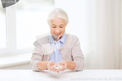 Image of happy senior woman with medicine at home