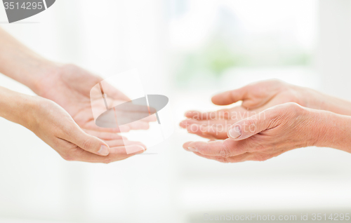 Image of close up of senior and young woman hands