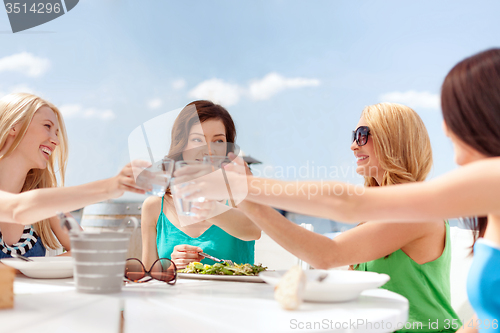 Image of smiling girls looking at tablet pc in cafe