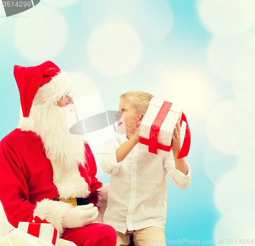 Image of smiling little boy with santa claus and gifts