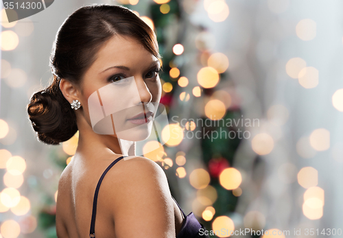 Image of woman with diamond earring over christmas lights