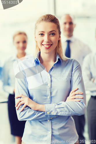 Image of smiling businesswoman with colleagues in office