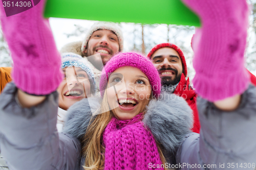 Image of smiling friends with tablet pc in winter forest