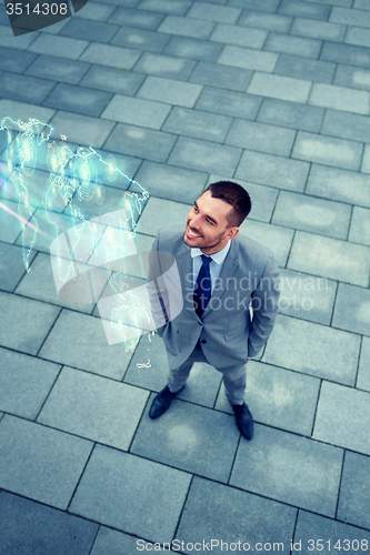 Image of businessman with world map hologram outdoors