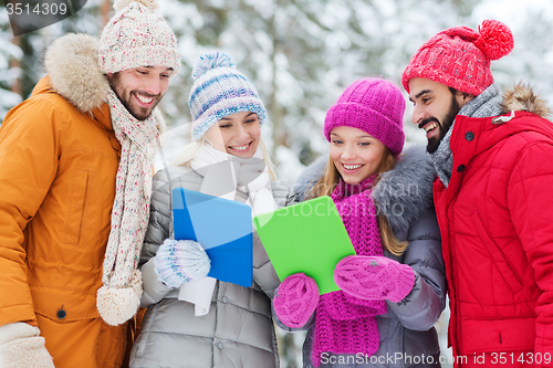 Image of smiling friends with tablet pc in winter forest