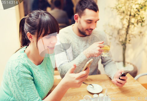 Image of smiling couple with smartphones drinking tea