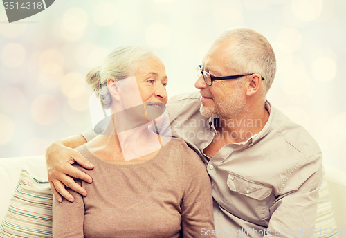 Image of happy senior couple hugging on sofa at home