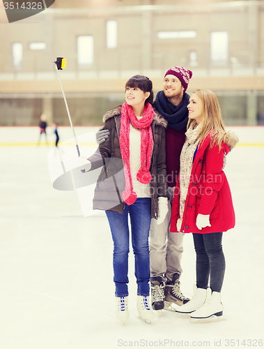 Image of happy friends with smartphone on skating rink