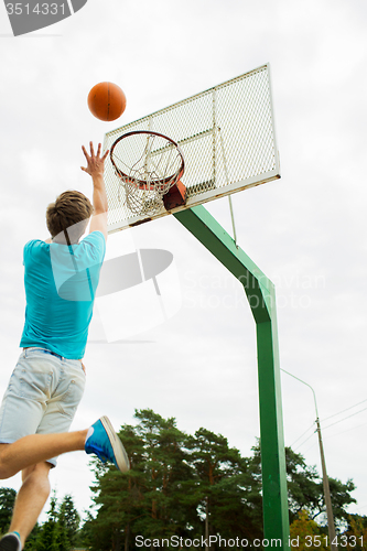 Image of young man playing basketball outdoors