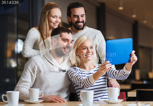 Image of happy friends with tablet pc taking selfie at cafe
