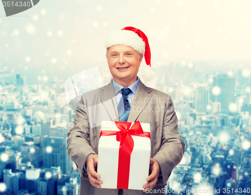 Image of smiling man in suit and santa helper hat with gift