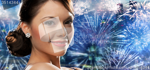 Image of happy woman with diamond earring over firework