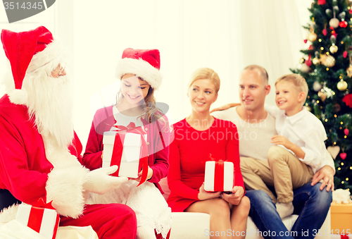 Image of smiling family with santa claus and gifts at home