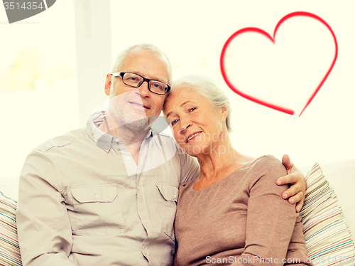 Image of happy senior couple hugging on sofa at home