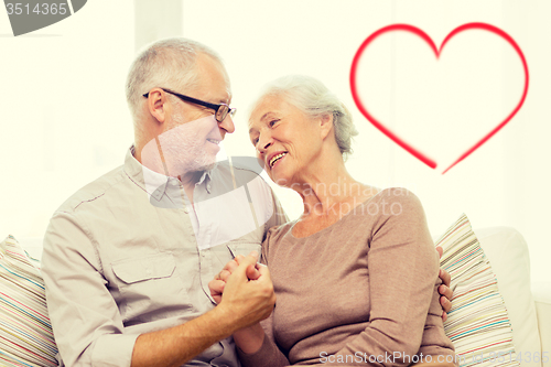 Image of happy senior couple hugging on sofa at home