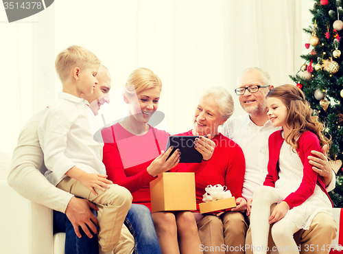 Image of smiling family with tablet pc and gift box at home