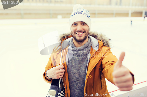 Image of happy young man showing thumbs up on skating rink