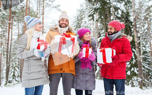 Image of happy friends with gifts in snowy winter forest