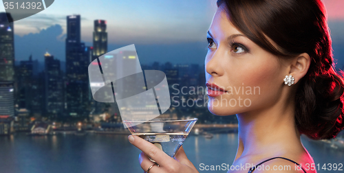 Image of smiling woman holding cocktail over night city