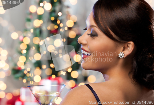 Image of woman face with cocktail over christmas lights