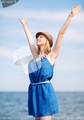 Image of girl with hands up on the beach