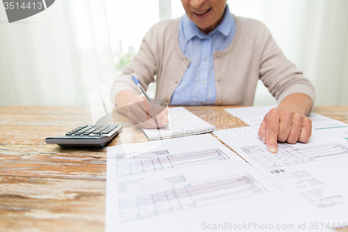 Image of senior woman with papers and calculator at home