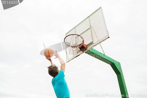 Image of young man playing basketball outdoors